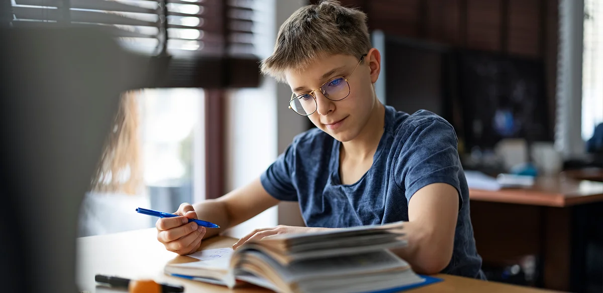 Student taking notes while reading a book